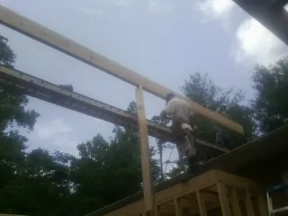 Carpenter setting a ridge beam over a new addition frame — Ice Dam Removal by Roofing Brothers in Urbandale