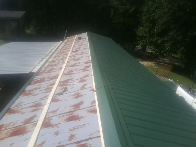 Old rusted panels beside newly installed green metal roofing — Wind Damage Roof Repair by Roofing Brothers in Urbandale