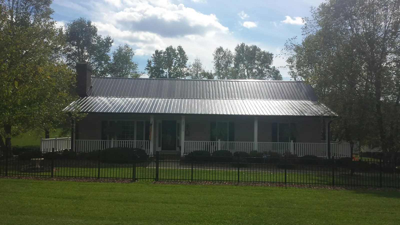 Gray metal roof on a brick ranch with a full width front porch — Gutter Guard Installation work by our crew in Urbandale