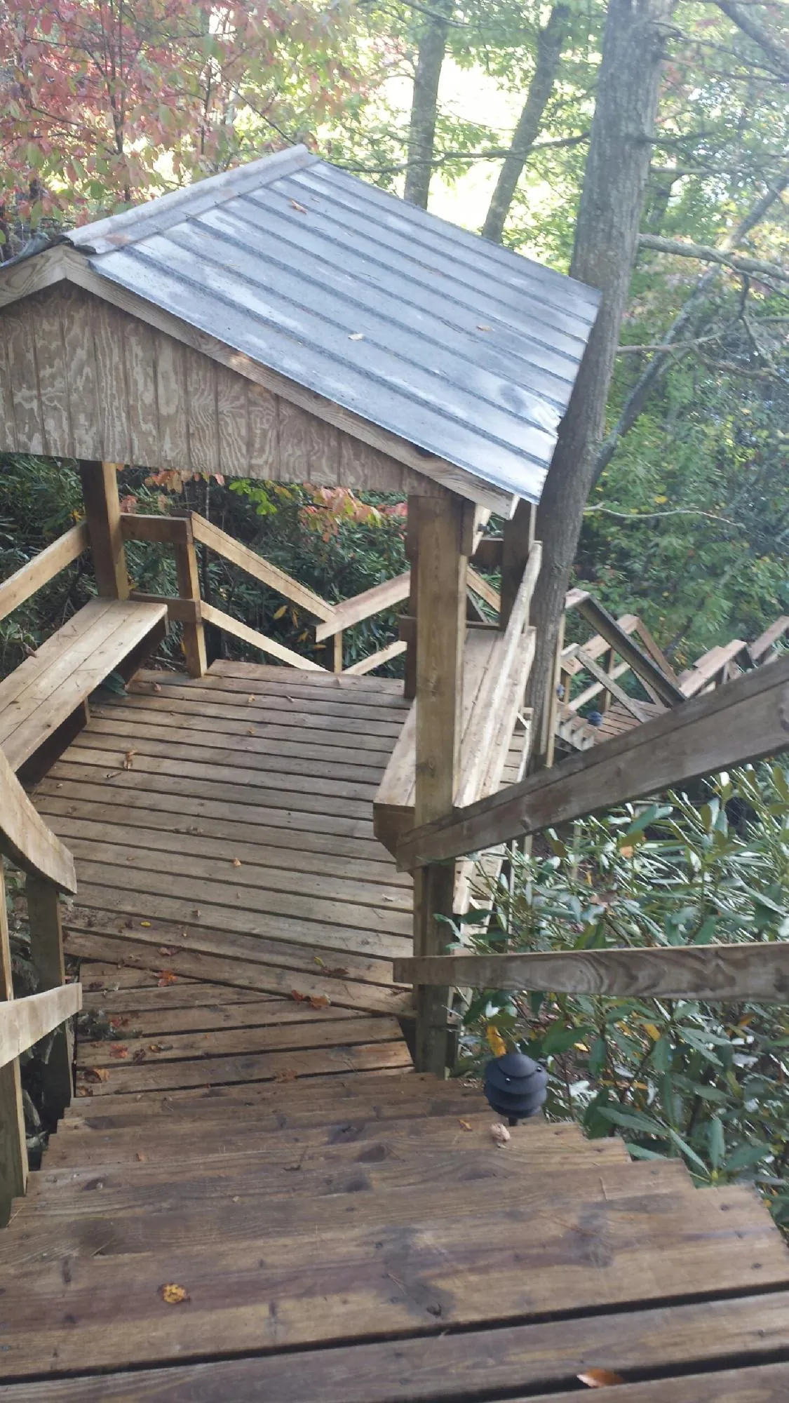 Metal roofed shelter over wooden steps on a wooded walkway — Skylight Repair & Installation work by our crew in Urbandale